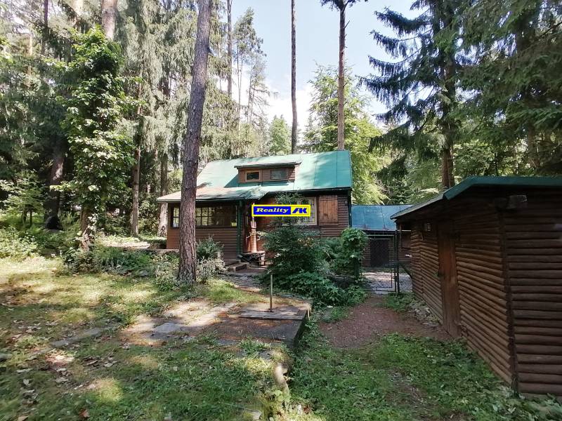 Chata obklopená lesom, symbolizujúca pokoj prírody, pripomína pamiatku na Hrdinov SNP.