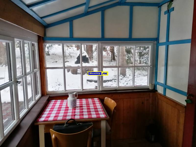 Zimná chata s dreveným interiérom, stolom z kockovaným obrusom, evokujúca Hrdinov SNP.