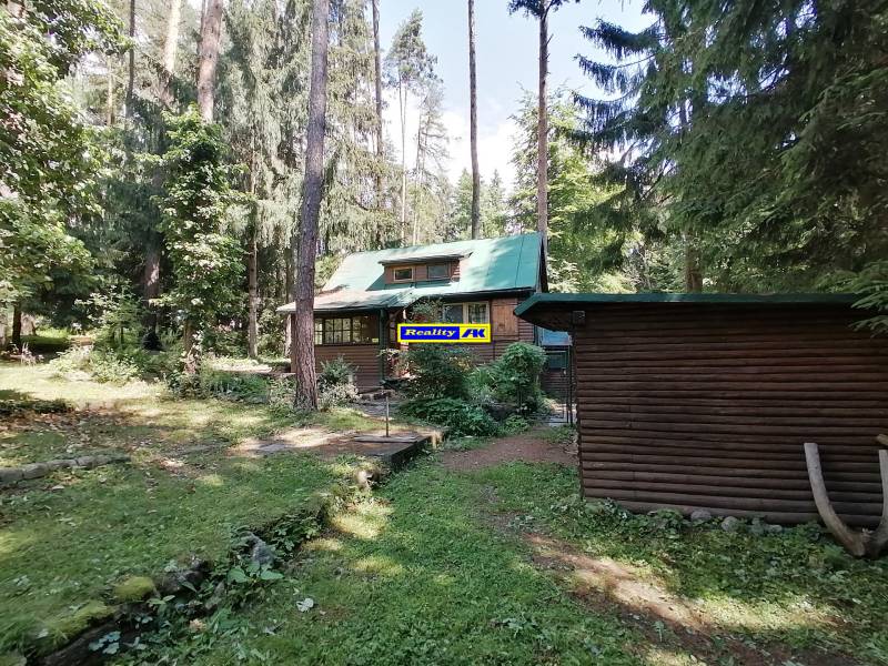 Chata obklopená vysokými stromami, ideálne miesto pre oddych v prírode a pokoj Hrdinov SNP.