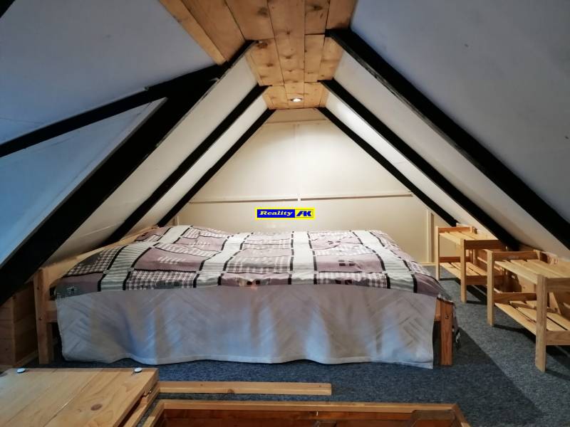 Podkrovná izba s posteľou a dreveným nábytkom v chate Hrdinov SNP.