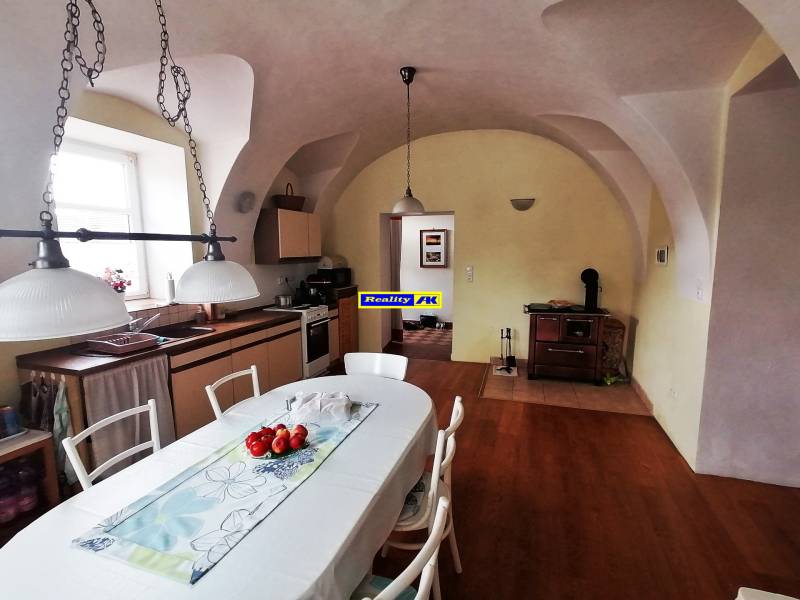 Jedáleň a kuchyňa v rodinnom dome s drevenou podlahou a rustikálnym nábytkom.