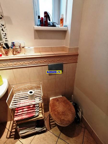 Kúpeľňa v rodinnom dome s oknom, uterákmi a toaletou s dekoračným sedákom.