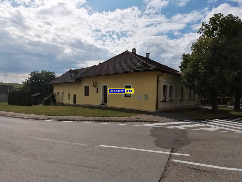 Rodinný dom v Turčianskych Tepliciach v Mošovciach, obklopený cestou a zeleňou pod oblakmi.