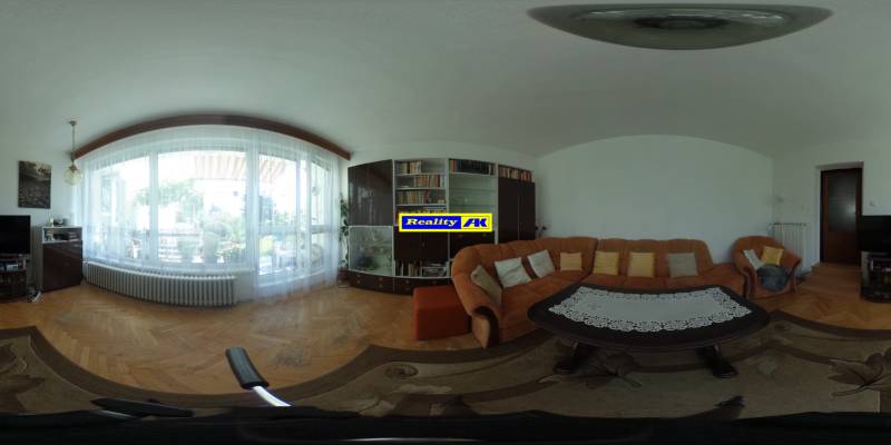 Obývacia izba v rodinnom dome s pohodlnou sedačkou a podlahou s dreveným dekorom.