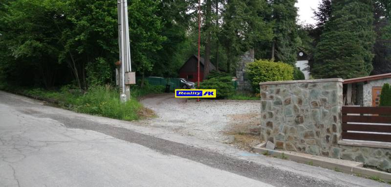 Rekreačné pozemky na Hrdinov SNP v Martine obklopené stromami a kamenným plotom.