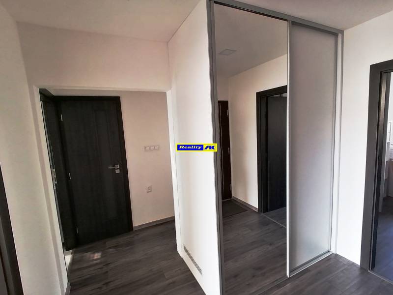 Vstupná chodba v 3-izbovom byte s podlahou s dreveným dekorom a vstavanou skriňou.