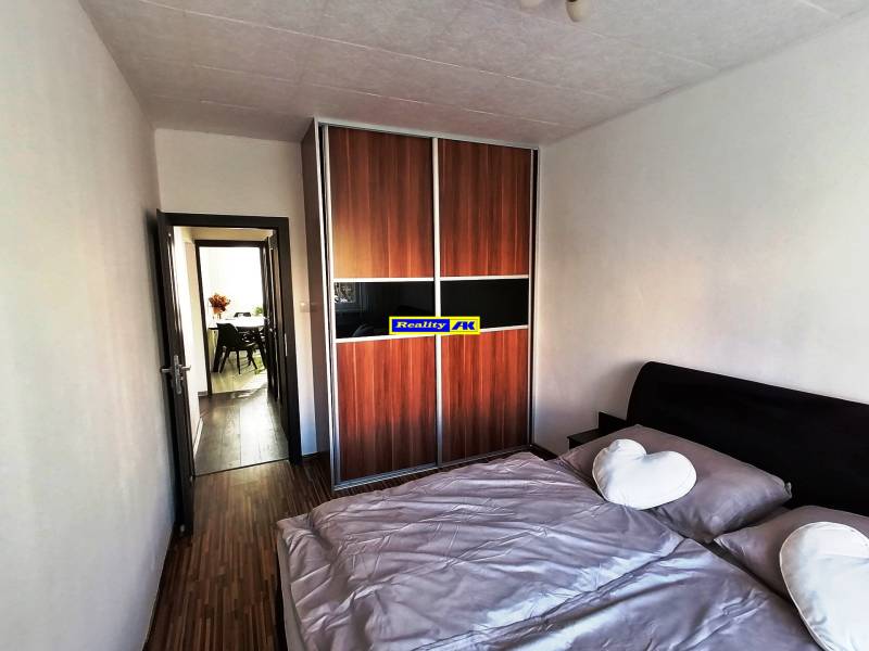 Spálňa v 3-izbovom byte s veľkou vstavanou skriňou a podlahou s dreveným dekorom.