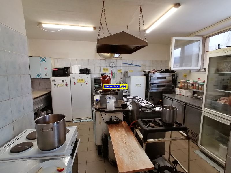 Kuchyňa v gastro priestoroch s plynovým sporákom, chladničkami a pracovnými doskami.