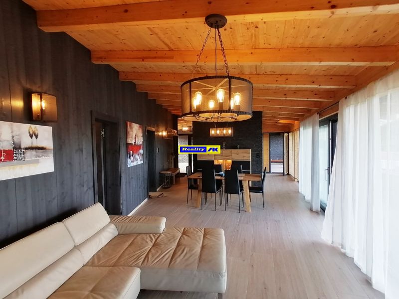 Obývacia izba vo vile s podlahou s dreveným dekorom a nástennými dekoráciami.