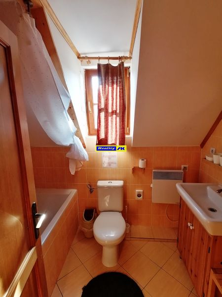 Kúpeľňa v chate so strešným oknom, vaňou a dreveným nábytkom.