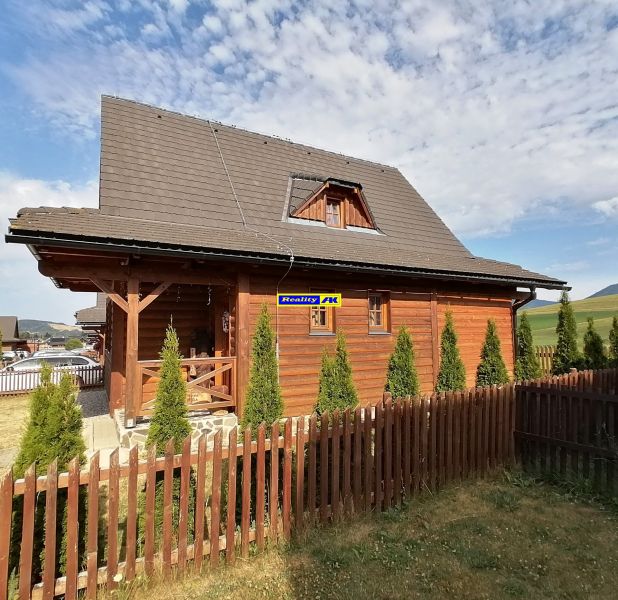 Drevená chata v Liptovskom Trnovci s upraveným plotom a ihličnanmi, Liptovský Mikuláš.