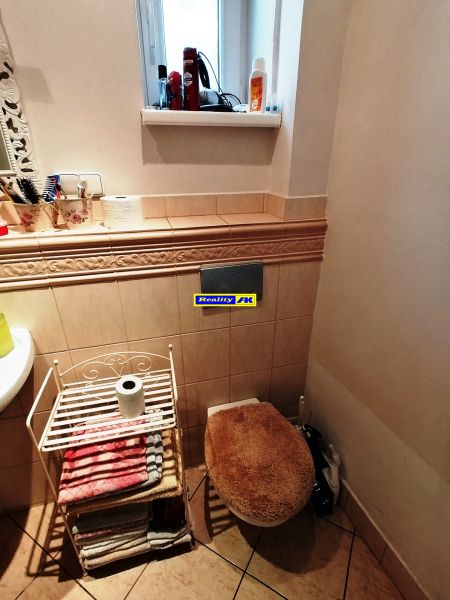 Kúpeľňa v rodinnom dome s oknom, uterákmi a toaletou s dekoračným sedákom.
