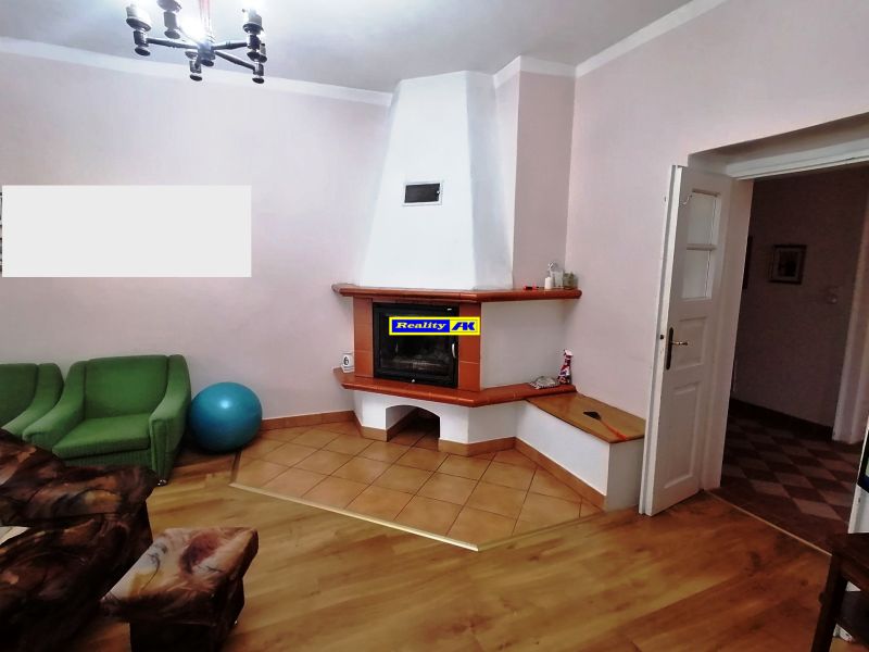Obývacia izba s krbom, zelenými kreslami a dekoráciami v rodinnom dome